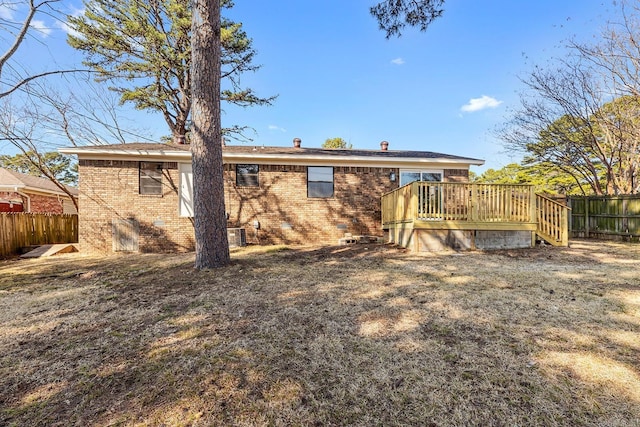 back of property featuring brick siding, fence, and a deck