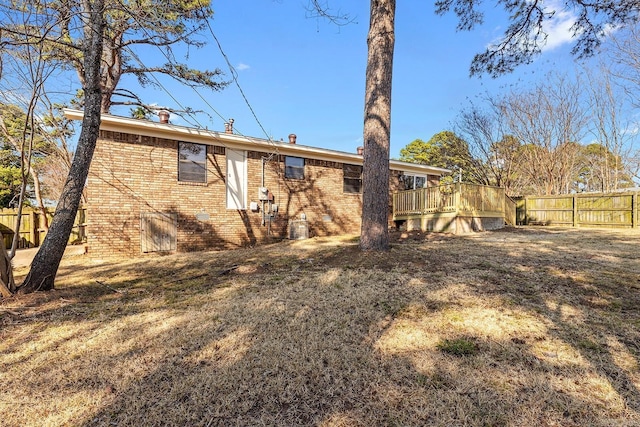 back of property with brick siding, fence, and a wooden deck