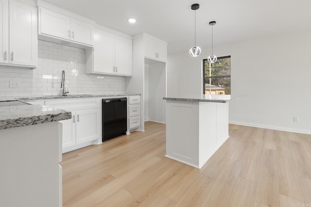 kitchen with white cabinets, light wood-style floors, light stone countertops, dishwasher, and tasteful backsplash