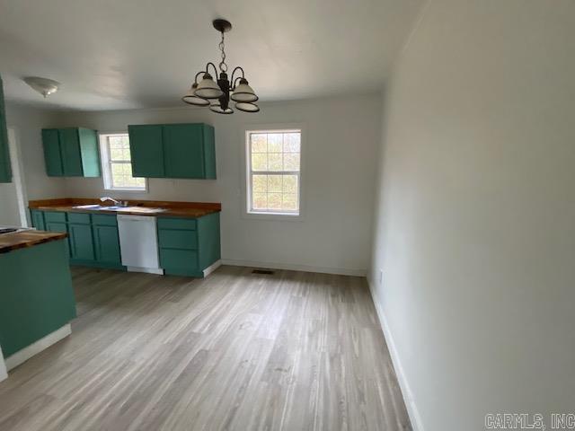 kitchen with dishwasher, baseboards, wood counters, and green cabinetry