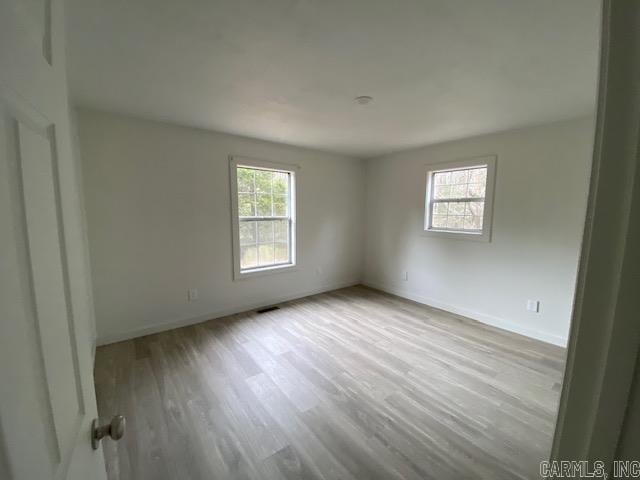 unfurnished room featuring plenty of natural light, wood finished floors, and baseboards