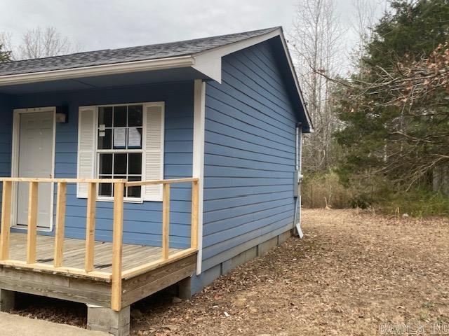 view of side of property featuring a porch and a shingled roof