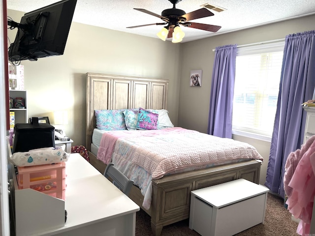 bedroom with a textured ceiling, ceiling fan, dark carpet, and visible vents