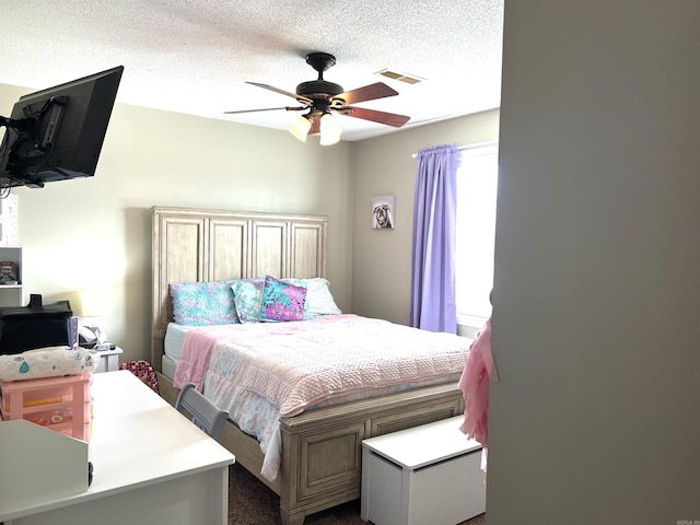 bedroom featuring a textured ceiling, visible vents, and a ceiling fan