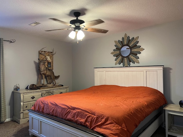 bedroom featuring a textured ceiling, ceiling fan, dark carpet, and visible vents