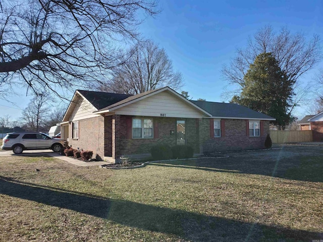 ranch-style home featuring brick siding, fence, and a front lawn