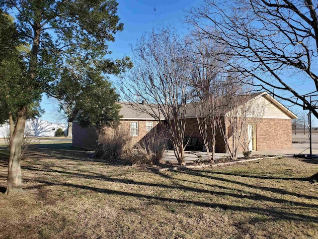 exterior space featuring brick siding and a yard