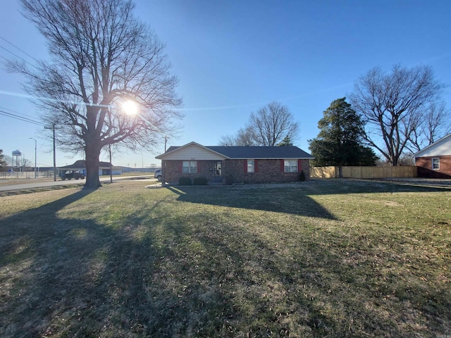 view of front facade with a front yard, fence, and brick siding