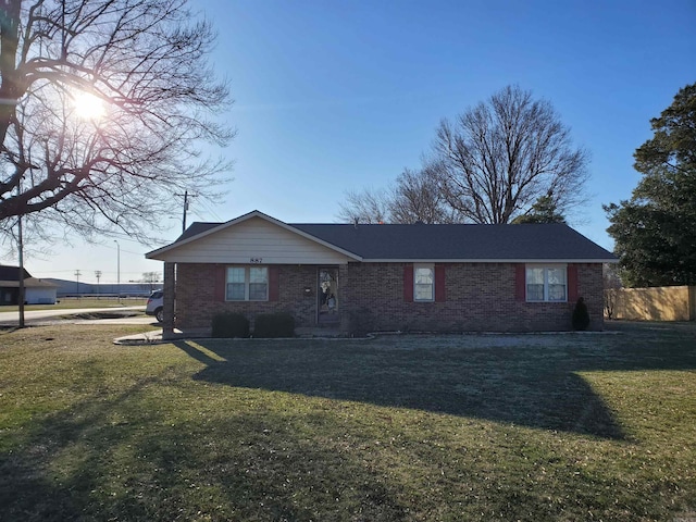 single story home featuring brick siding, a front lawn, and fence