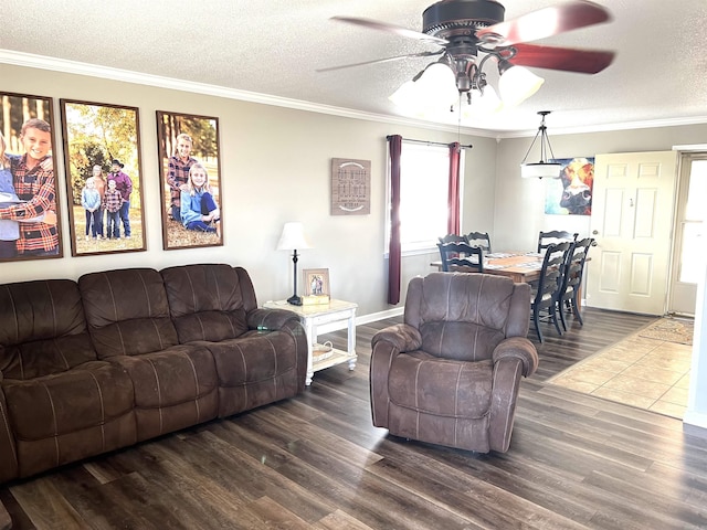 living area with a textured ceiling, ceiling fan, dark wood finished floors, and crown molding