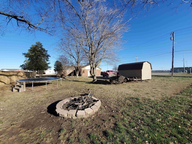 view of yard with a storage shed, a trampoline, a fire pit, and an outdoor structure