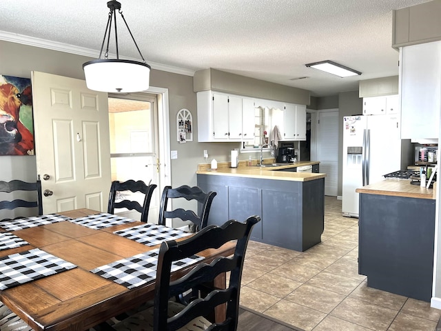 kitchen featuring ornamental molding, a peninsula, light countertops, white fridge with ice dispenser, and a sink