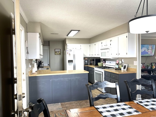 kitchen with white appliances, a peninsula, light countertops, white cabinetry, and a sink