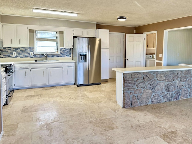 kitchen with appliances with stainless steel finishes, light countertops, a sink, and separate washer and dryer