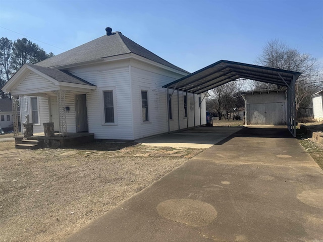 view of front of house featuring a carport, roof with shingles, and driveway