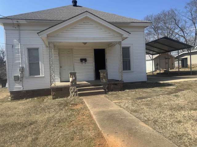 view of front of property featuring covered porch, a shingled roof, and a carport