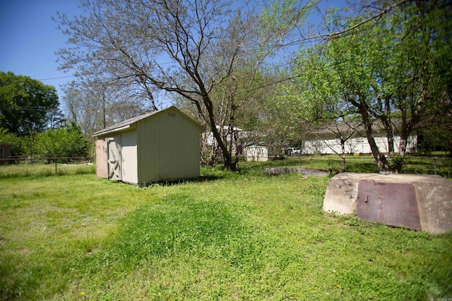 view of yard featuring an outdoor structure, fence, and a shed