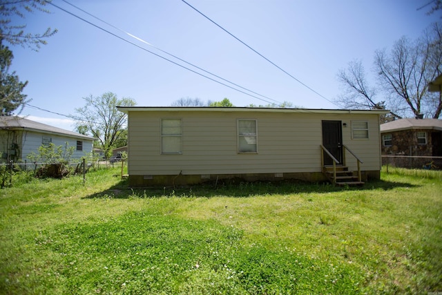 back of property with crawl space, fence, a lawn, and entry steps