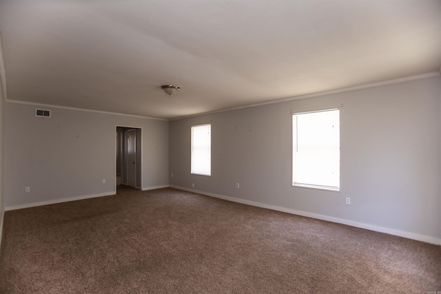 unfurnished room featuring carpet, visible vents, crown molding, and baseboards