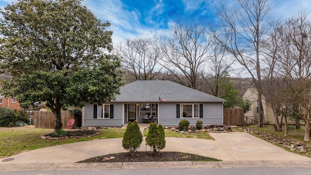 ranch-style home featuring fence, concrete driveway, and roof with shingles