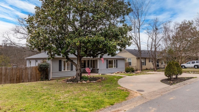 view of front facade featuring driveway, a front yard, and fence