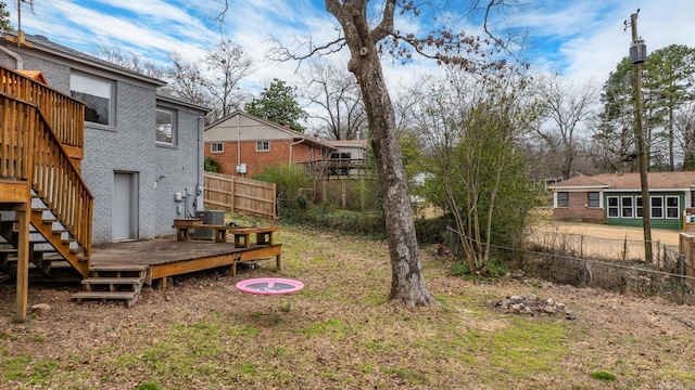 view of yard with a deck, central AC, fence, and stairs