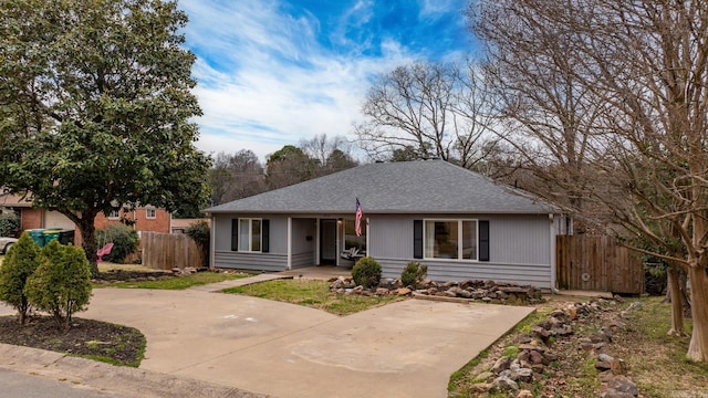 ranch-style home featuring fence and roof with shingles