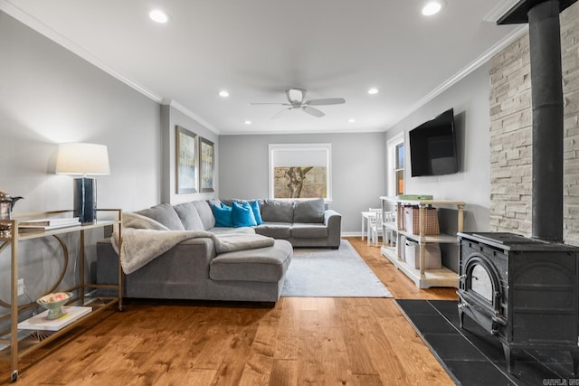 living area featuring a wood stove, a healthy amount of sunlight, ceiling fan, and wood finished floors