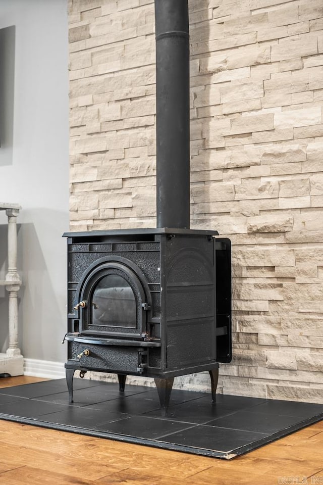 room details featuring wood finished floors, a wood stove, and baseboards