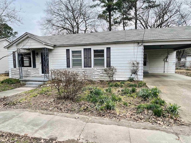 single story home with stone siding, an attached carport, and driveway