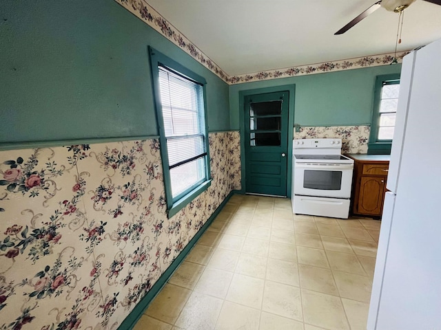 kitchen with white appliances, wainscoting, plenty of natural light, and wallpapered walls