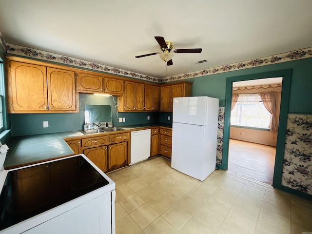 kitchen featuring white appliances, brown cabinets, a sink, and visible vents