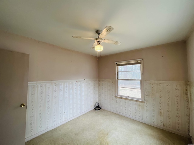 spare room featuring carpet floors, a ceiling fan, baseboards, and wallpapered walls