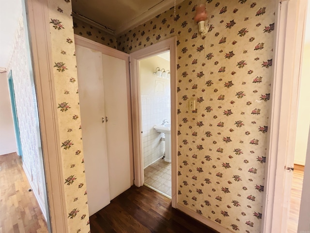 bathroom with wallpapered walls, crown molding, and wood finished floors