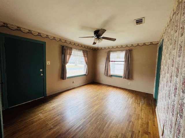 unfurnished room with visible vents, ceiling fan, baseboards, and wood finished floors