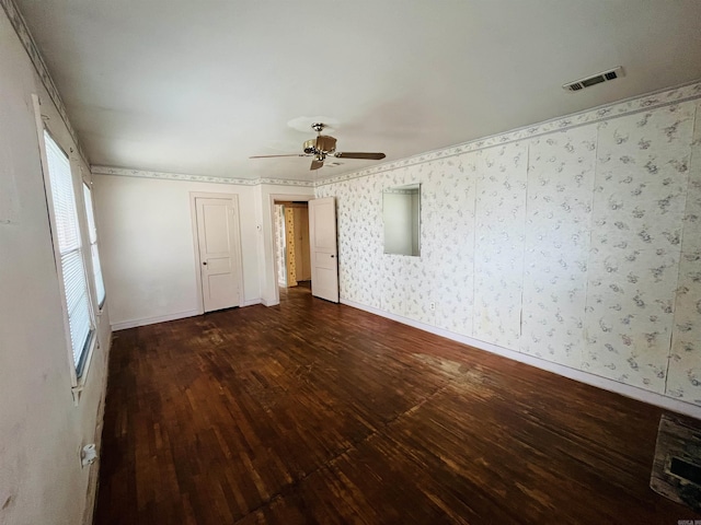 spare room with dark wood finished floors, visible vents, ceiling fan, baseboards, and wallpapered walls