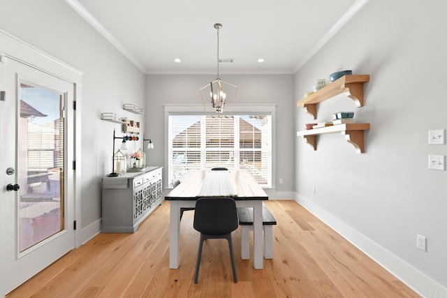 dining room featuring light wood-style floors, crown molding, baseboards, and a notable chandelier