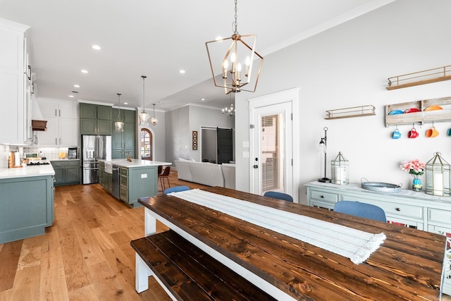 dining area with light wood-type flooring, crown molding, recessed lighting, and a barn door