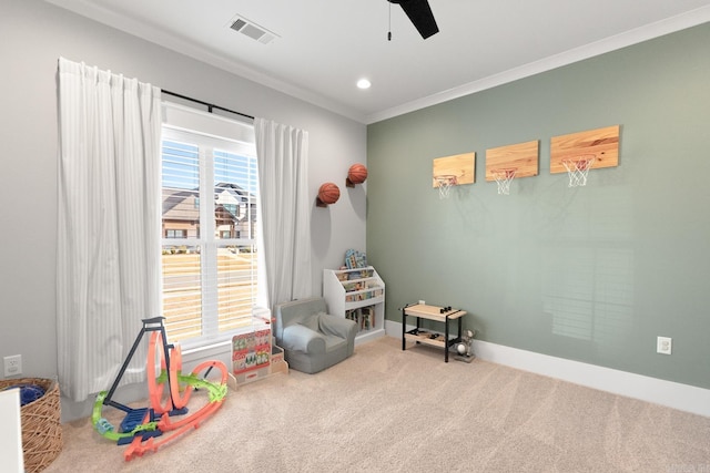 recreation room featuring baseboards, visible vents, a ceiling fan, carpet, and crown molding