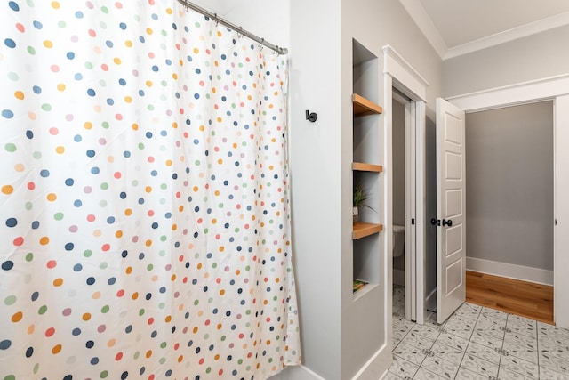 bathroom featuring ornamental molding, a shower with curtain, toilet, and baseboards