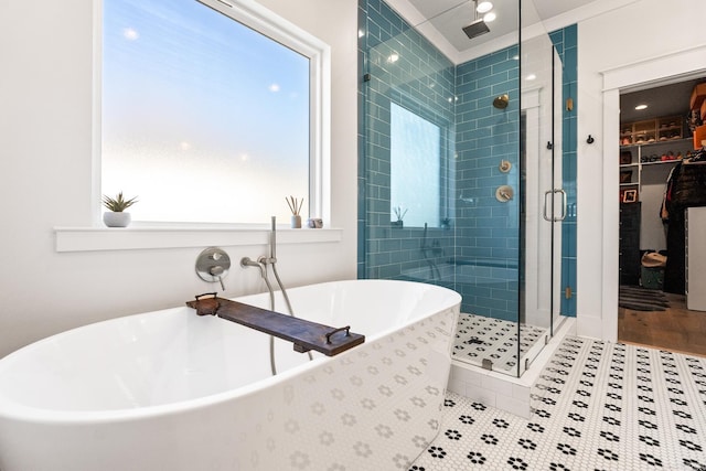 full bathroom with a freestanding bath, a stall shower, a walk in closet, and tile patterned floors