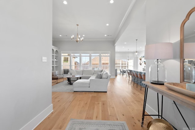 living area featuring baseboards, crown molding, light wood-type flooring, a chandelier, and recessed lighting