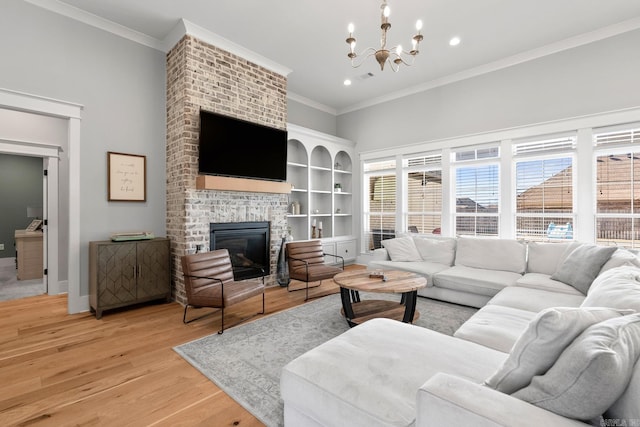 living room with a fireplace, light wood-style flooring, ornamental molding, a chandelier, and baseboards