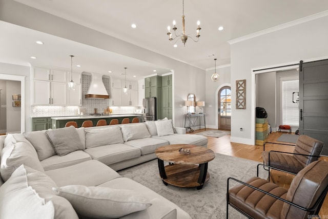 living area with a barn door, baseboards, light wood-style flooring, crown molding, and recessed lighting