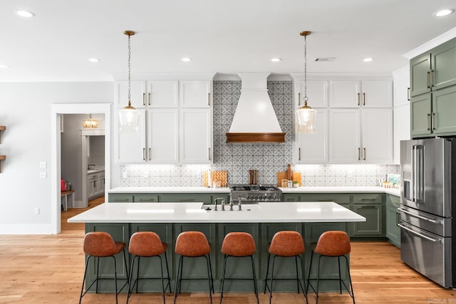 kitchen with light countertops, custom exhaust hood, stainless steel fridge with ice dispenser, a kitchen bar, and green cabinetry