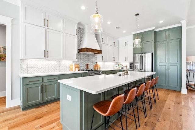 kitchen featuring stainless steel appliances, premium range hood, a sink, and green cabinetry