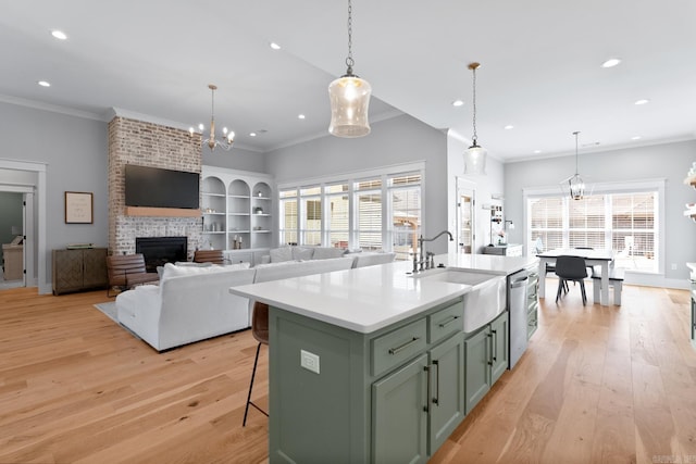 kitchen with a brick fireplace, a notable chandelier, light wood-style flooring, and a sink