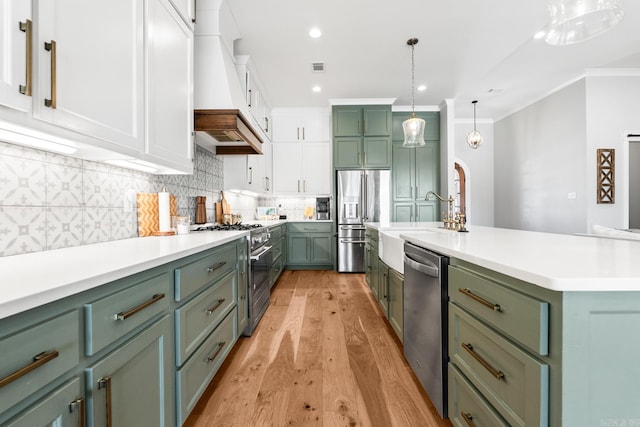 kitchen featuring stainless steel appliances, tasteful backsplash, a sink, green cabinetry, and premium range hood