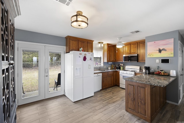 kitchen featuring white appliances, brown cabinetry, a peninsula, french doors, and a sink