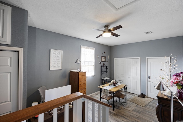 bedroom with a textured ceiling, two closets, wood finished floors, and visible vents